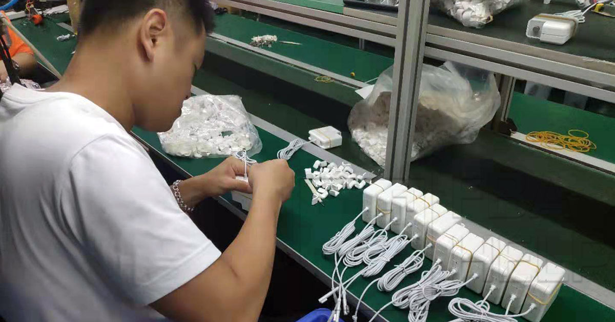 Inspector checking MacBook chargers on factory floor